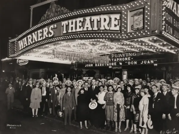 Menschenmenge vor dem hell erleuchteten Warner’s Theatre bei Nacht.